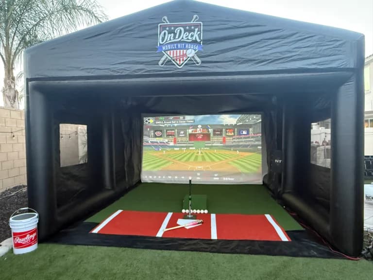 The Mini Hit House with its front open, tee set at the plate and a stadium on the screen